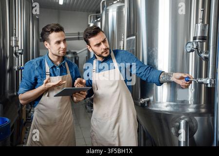 Two Men Discussing Brewing Process In Modern Brewery, Business Concept Stock Photo