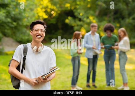 Portrait Of Happy Asian Student Guy With Workbooks And Backpack Posing Outdoors Stock Photo