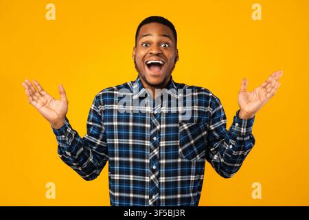 Surprised African Guy Posing With Opened Mouth Over Yellow Background Stock Photo