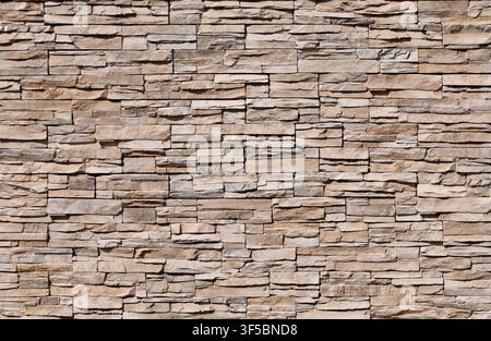 Stone coating wall made of striped stacked bricks of natural brown rocks. Panels for exterior. Background and texture. Stock Photo
