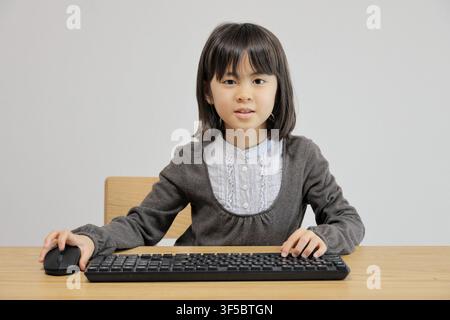 Japanese student girl using PC mouse (8 years old) Stock Photo