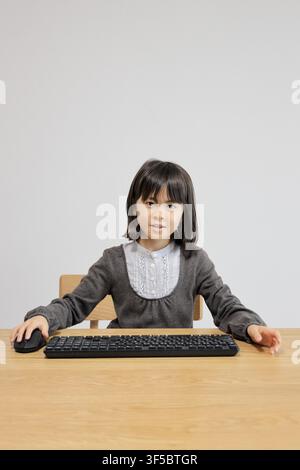 Japanese student girl using PC mouse (8 years old) Stock Photo