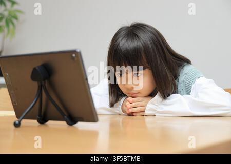 Japanese student girl watching video on tablet PC (8 years old) Stock Photo