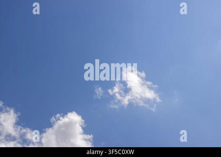 A peaceful clear blue sky backdrop with a solitary white fluffy cloud in the center. High Quality Photo Stock Photo