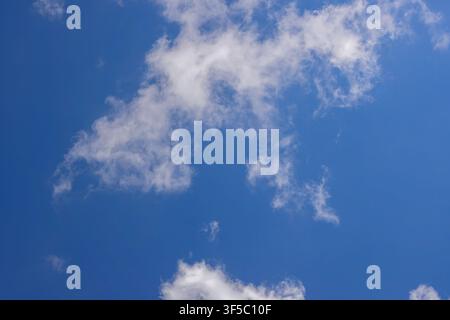 Soft wispy white clouds scattered gracefully across a bright blue summer sky. High Quality Photo Stock Photo