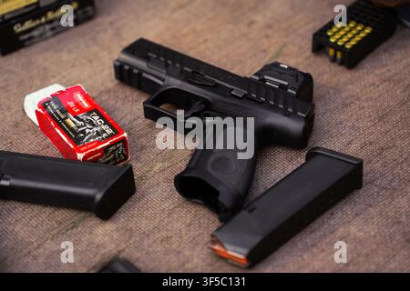 Black semi automatic pistol with tactical sights, spare magazines, and ammunition box. Modern handgun weapon system, firearm self defense training, tactical shooting equipment, gun ownership Stock Photo