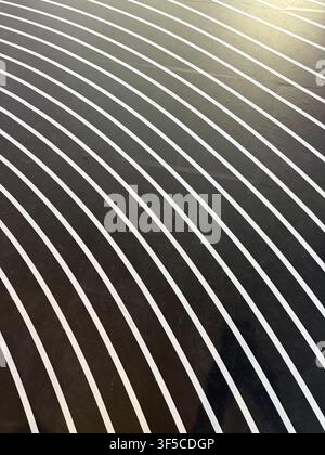 Abstract curved white lines on black floor creating geometric minimalist pattern Stock Photo