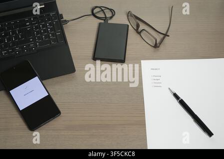 A workstation featuring a "Project" planning sheet, a laptop, and an external hard drive for data backup. Stock Photo