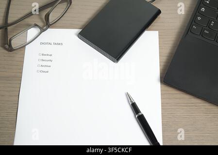 Macro view of a workstation featuring glasses, a "Digital Tasks" list, and an external hard drive. Stock Photo