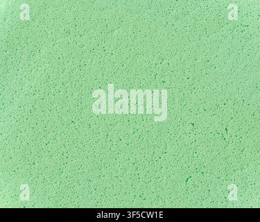 light green sponge texture background, porous foam surface with tiny bubbles and holes, macro close-up view, abstract cleaning material Stock Photo