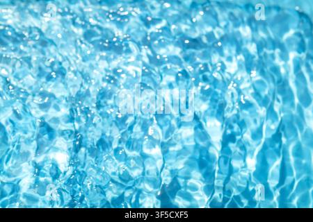 Sunlit blue pool water with shimmering ripples and clear reflective surface evoking calm summer refreshment. Stock Photo