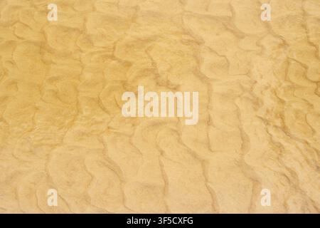 Top down view of golden beach sand with rippled texture patterns and natural sunlight, aerial macro perspective, wind swept sediment, coastal geology, natural geometric abstract Stock Photo