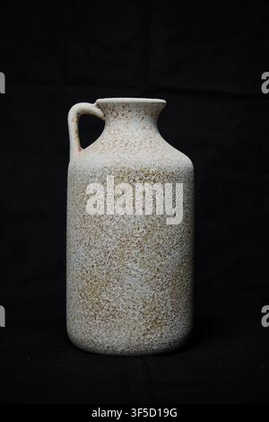 Rustic speckled ceramic jug with a handle on a dark background Stock Photo