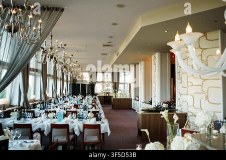 Elegant banquet hall set for a wedding reception featuring long tables, crystal chandeliers, and sophisticated luxury venue decor Stock Photo