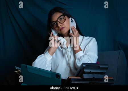 Woman juggling multiple calls managing overwhelming office communication Stock Photo