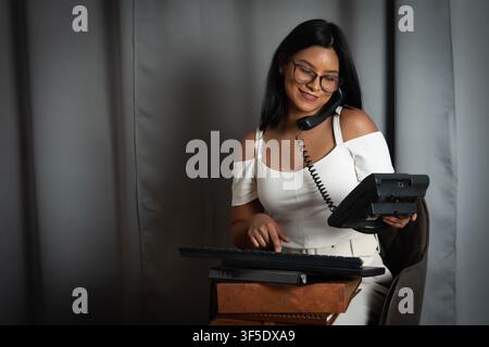 Businesswoman talking on phone typing on keyboard Stock Photo