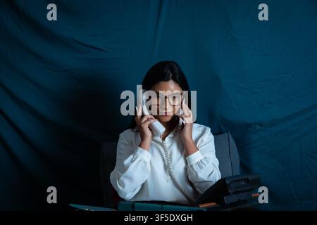 Businesswoman multitasking with multiple telephones in office Stock Photo
