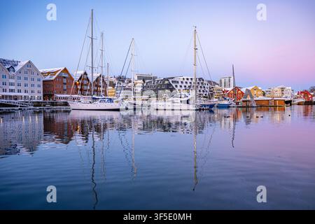 Sailing boats and Pust floating sauna reflected in calm Tromso harbour during soft pastel winter twilight in Arctic Norway. Stock Photo