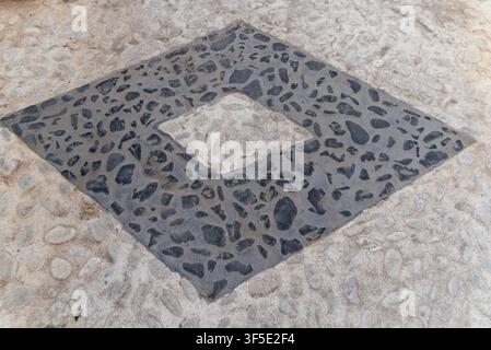 Close up of decorative stone pavement with black mosaic inlay and natural pebble texture. Traditional geometric paving pattern suitable as an abstract Stock Photo