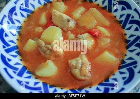 High angle shot of a hot plate of Marmitako, a classic Spanish fish stew featuring tender chunks of tuna and potatoes in a rich paprika tomato sauce. Stock Photo