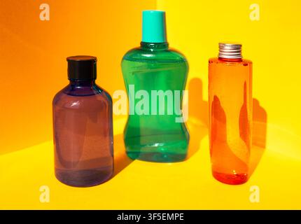 Three plastic bottles of different shapes and colors displayed against a yellow background, highlighting their unique designs and vibrant hues Stock Photo