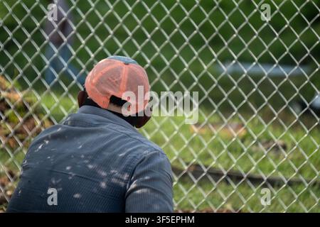 Worker waits behind a security fence Stock Photo