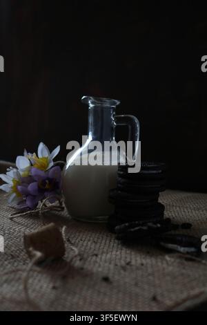 still life with flowers, bottle of milk, and cookies Stock Photo