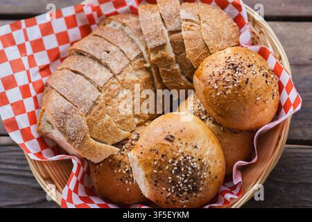 Artisan Sourdough Bread and Seeded Rolls Served in Basket on Wooden Table Stock Photo