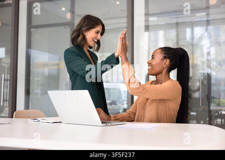 Two successful businesswomen celebrating team achievement in modern office Stock Photo