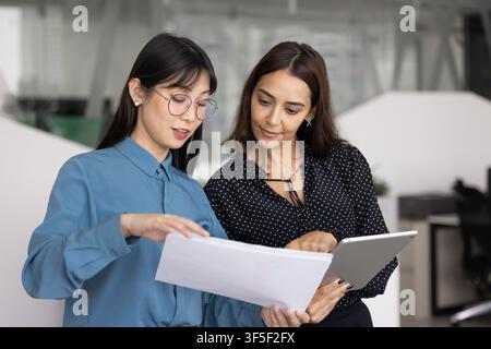 Two businesswomen discussing project documents in office Stock Photo