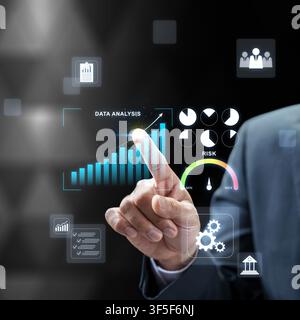 A professional businessman interacts with a futuristic holographic interface showing growth charts, data analytics, and risk management tools to optim Stock Photo