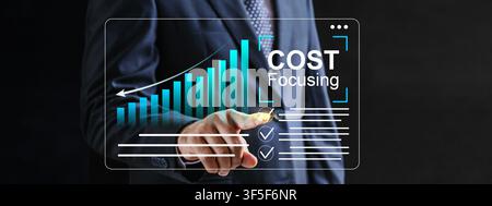 Businessman in a suit interacting with a virtual dashboard showing bar charts and cost focusing text, highlighting strategic financial management and Stock Photo