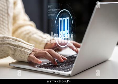 Close up of hands typing on a laptop with a holographic interface representing digital archiving, document management, and paperless office solutions Stock Photo