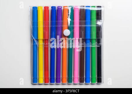 A collection of twelve vibrant multi-colored felt-tip markers in a transparent plastic pouch with a white button snap, isolated on a clean white backg Stock Photo
