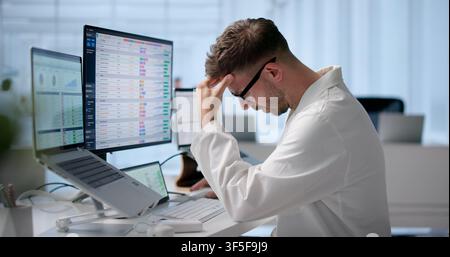 Tired Medical Coder Manages Hospital Billing Codes Late At Laptop. Stock Photo