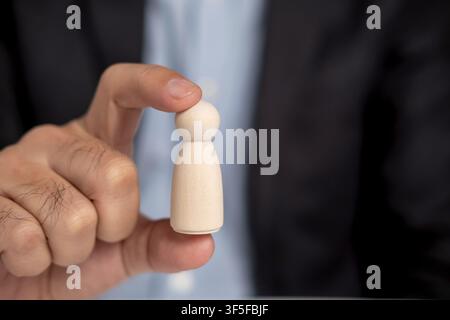 Close up businessman pick up leads wooden dolls. Successful business team leader. Leadership concept. Stock Photo