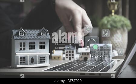 Proptech concept: Online real estate search and property management with digital icons over miniature houses on a laptop keyboard. Stock Photo