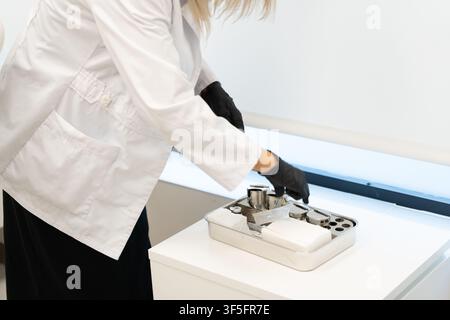 Healthcare worker wearing a lab coat and gloves arranging sterile instruments on a tray Stock Photo