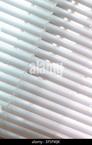 Close-up of sunlight passing through window blinds, creating abstract geometric lines and soft shadows Stock Photo