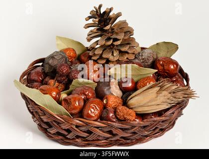 Decorative wooden basket with dried fruits and leaves on a white background, natural home decor arrangement still life Stock Photo
