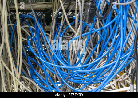 Tangled network and ethernet cables connected in server rack illustrating data communication infrastructure information technology maintenance and con Stock Photo