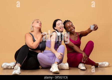 Cheerful Diverse Multiethnic Females In Sportswear Taking Selfie On Smartphone After Training Stock Photo