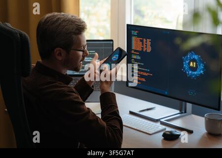 Programmer communicating with an AI agent through a smartphone, using a voice digital assistant on phone for software development and vibe coding. Man talking with Artificial intelligence powered app Stock Photo