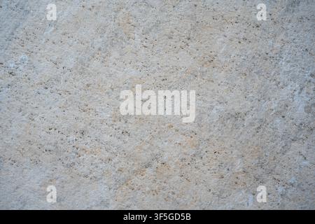 A closeup view shows a light beige stone or concrete surface with fine speckles and natural texture. Stock Photo