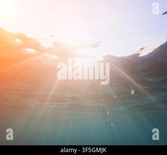 Vibrant underwater rays, glowing sunbeams penetrating crystal clear sea water illuminating floating particles and marine life Stock Photo
