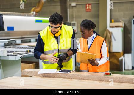 Multiracial workers collaborating in wood processing factory Stock Photo