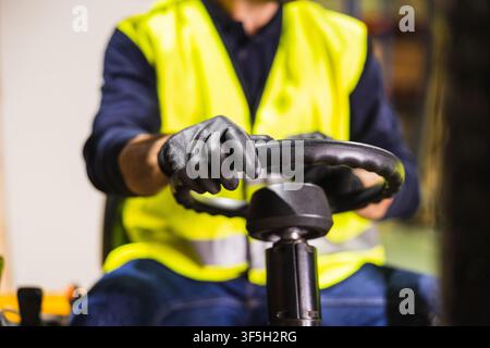 Worker operating forklift in warehouse or lumberyard Stock Photo