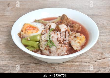 boiled fish and shrimp meatball with morning glory topping mashed pork couple creamy egg in spicy red sauce tom yum soup on bowl Stock Photo