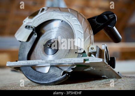 Circular saw on workbench in workshop. Professional power tool for cutting wood lumber during construction and carpentry work. Close up sharp metal bl Stock Photo
