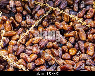 Sweet organic dried dates are spread out on branches in a local market. The close-up view shows the rich color and texture of the dates. Stock Photo